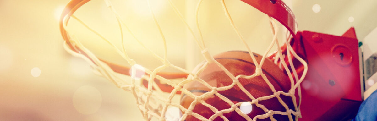 Orange basketball ball flying into the basketball hoop.