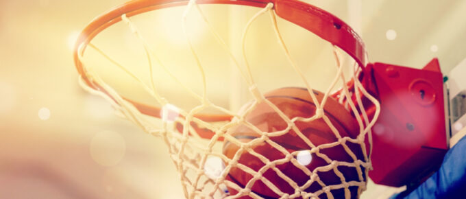 Orange basketball ball flying into the basketball hoop.