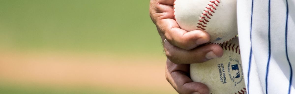 A man holding two white baseballs.