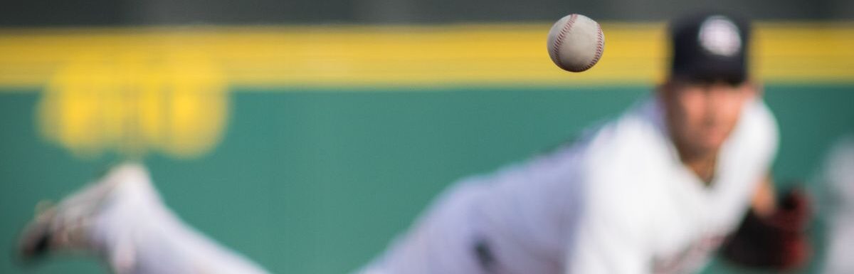 A baseball in motion with pitcher in background.