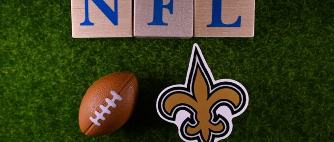 The emblem of the New Orleans Saints football club on the green lawn of the stadium.