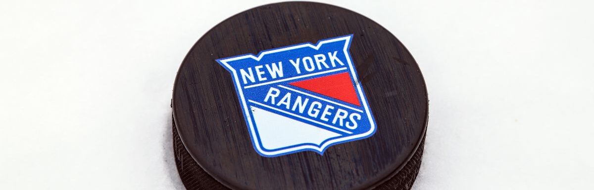 New York Rangers logo on Ice hockey puck outdoors in snow.