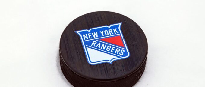 New York Rangers logo on Ice hockey puck outdoors in snow.