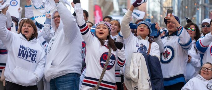 Fans wave for the TV cameras at the Winnipeg Whiteout street party during Game 1 of the Stanley Cup playoff game of the Winnipeg Jets versus the St. Louis Blues.