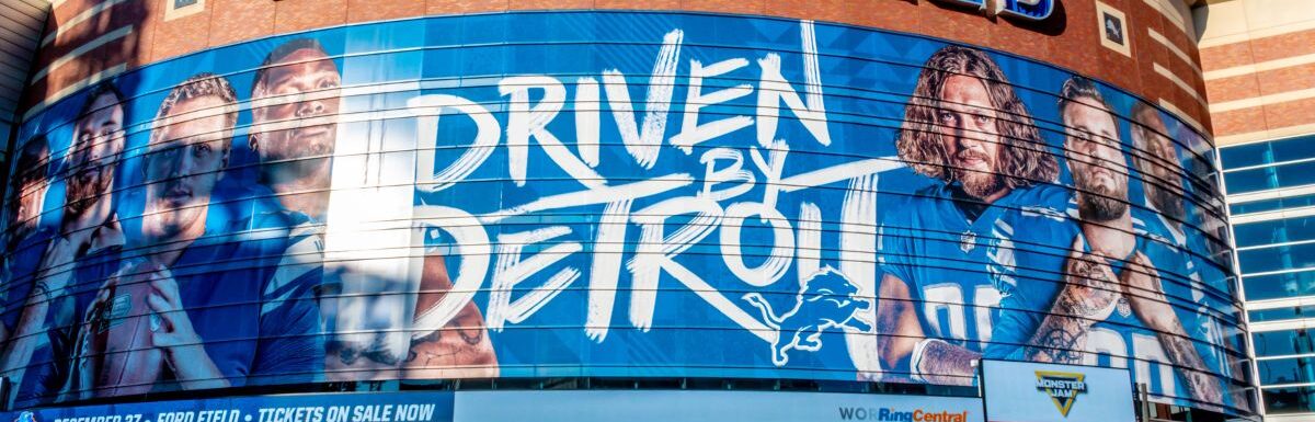 Horizontal, medium closeup of "Ford Field" Detroit Lions' football field stadium's exterior facade brand and logo signage on a sunny day.