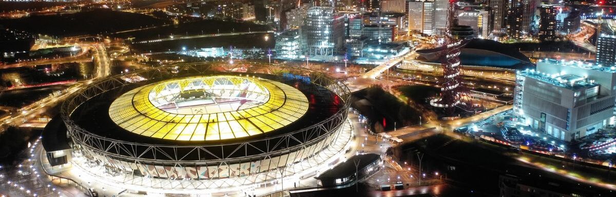 Aerial drone night shot of iconic illuminated London Stadium in Queen Elisabeth park, London, United Kingdom.