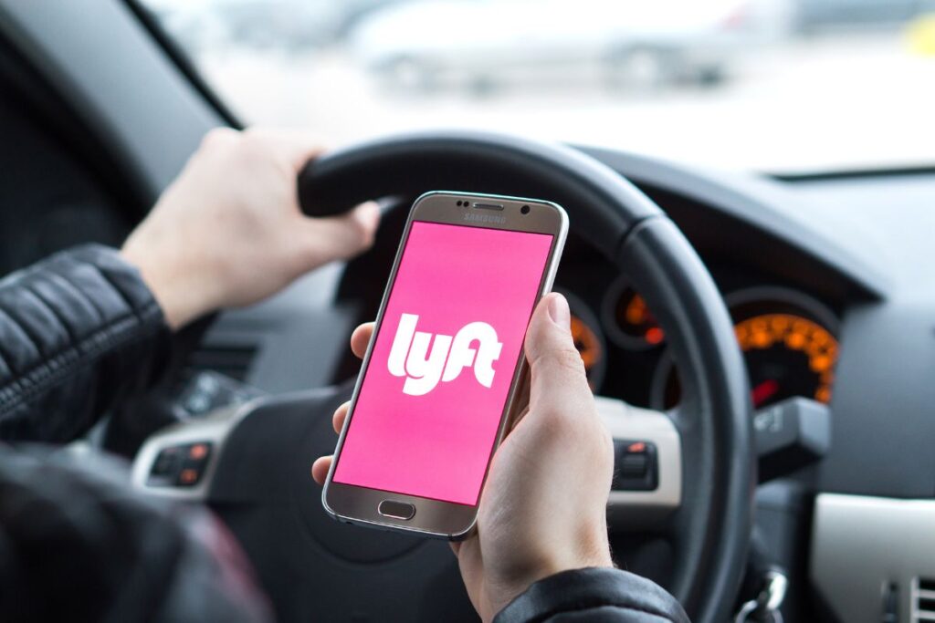 Lyft driver holding smartphone inside a car.