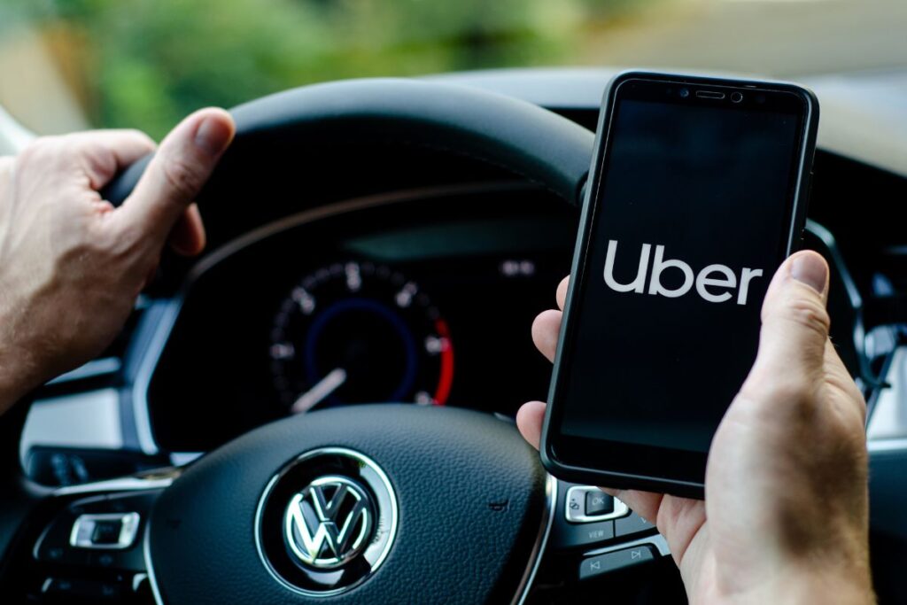 Uber driver holding smartphone inside a Volkswagen car.