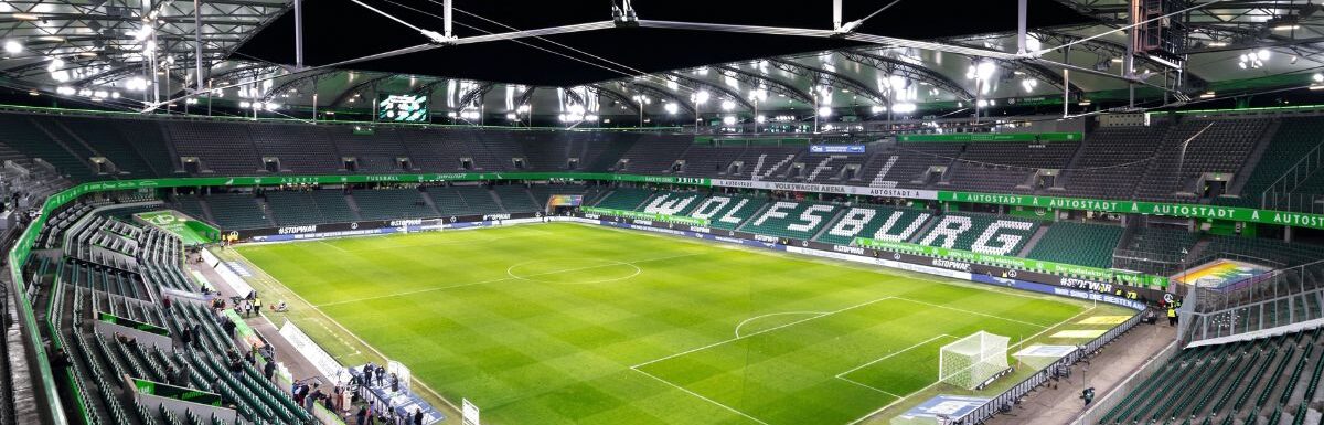 Panoramic wide-angle night view inside illuminated empty Volkswagen Arena stadium.