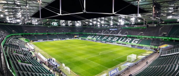 Panoramic wide-angle night view inside illuminated empty Volkswagen Arena stadium.